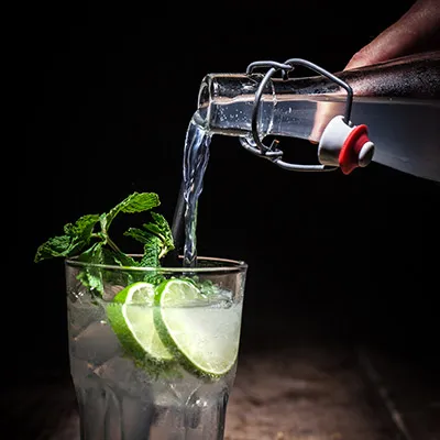 Hauslimonade wird in ein Glas mit Minze und Limette gegossen
